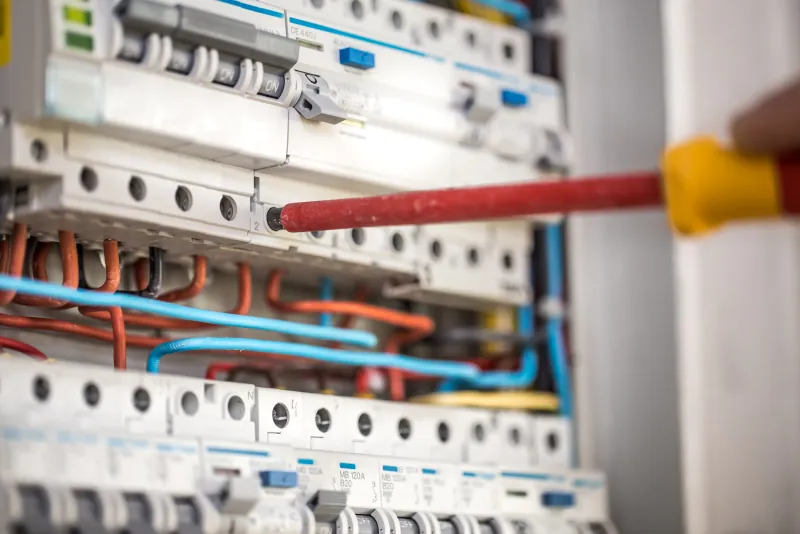 Elektricien werkt met een schroevendraaier aan de installatieautomaten in een groepenkast