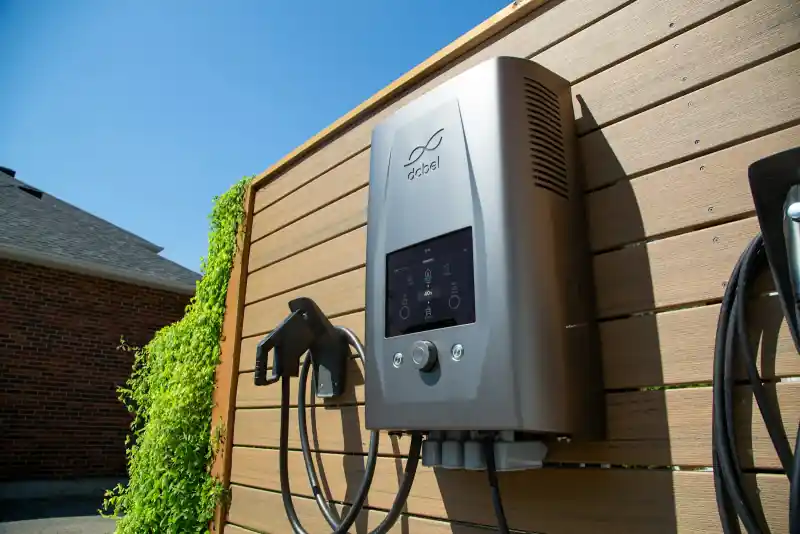 Laadpaal voor de elektrische auto aan een houten gevel van een woning