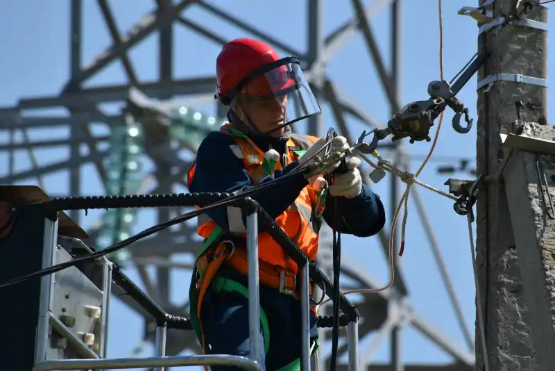Monteur met helm werkt hoog aan een elektriciteitsmast